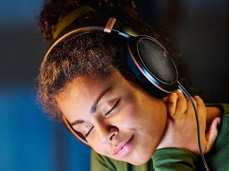 Person wearing Sennheiser open-back headphones, eyes closed, in immersive listening